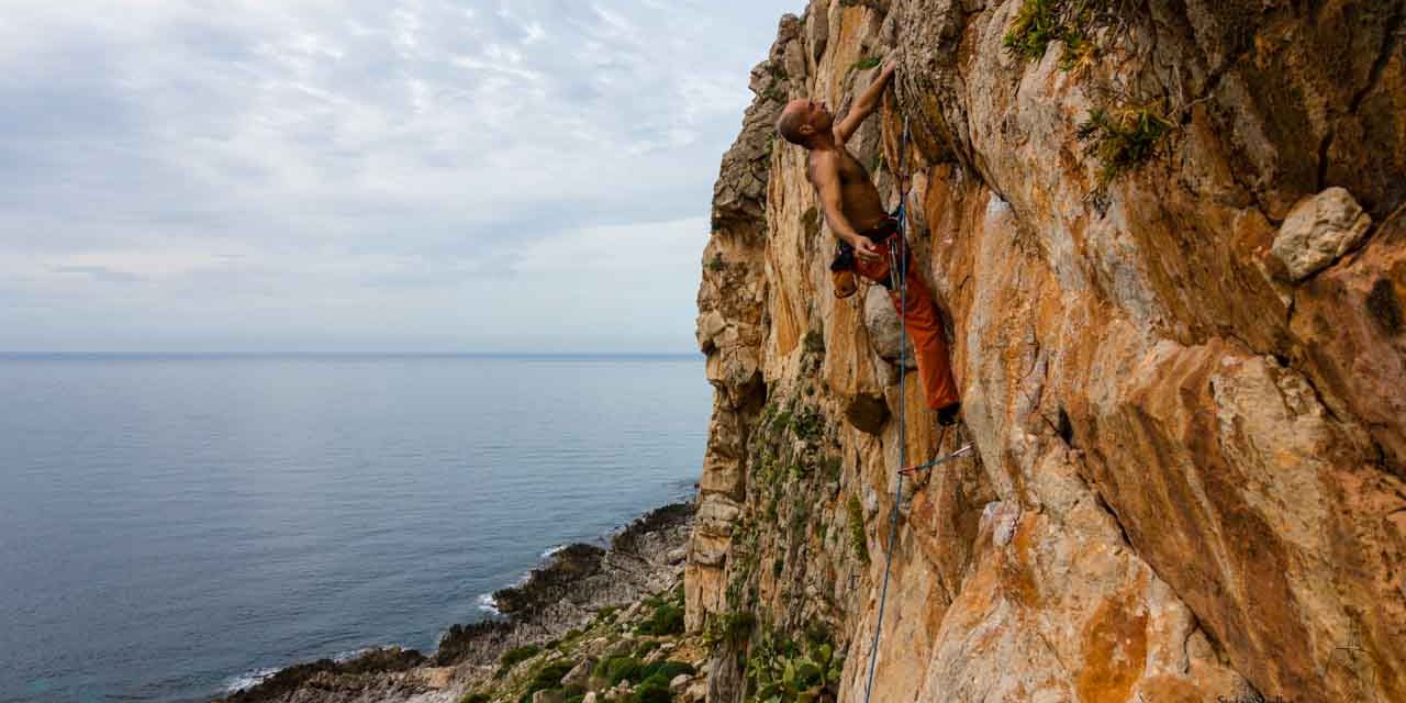 Kletterer über dem Meer in steiler Wand