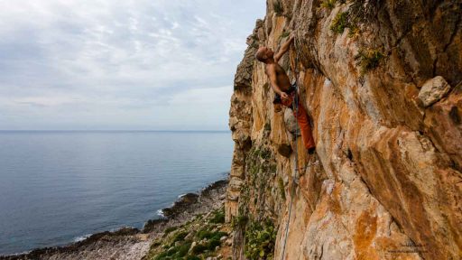 Kletterer über dem Meer in steiler Wand