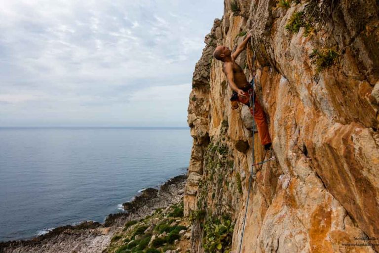 Kletterer über dem Meer in steiler Wand